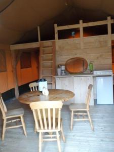 a wooden table and chairs in a room with a kitchen at Hoeveheikant Tenten in Lage Mierde