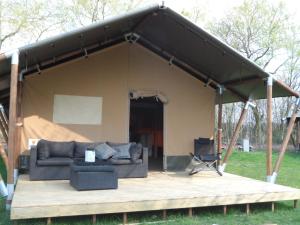 a tent with a couch on a wooden deck at Hoeveheikant Tenten in Lage Mierde