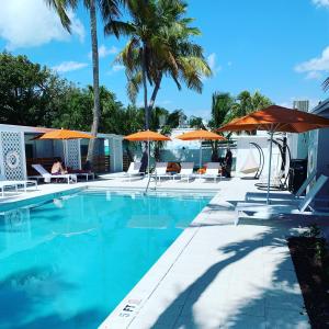 a swimming pool with orange umbrellas and chairs at Sunset Inn in Islamorada +22 photos