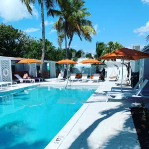 a beach area with umbrellas, chairs, and a pool at Sunset Inn in Islamorada