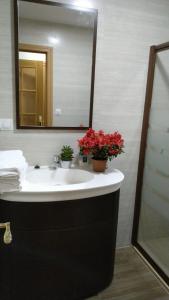 un bagno con lavandino, specchio e fiori rossi di Apartamento el Torreón a Setenil