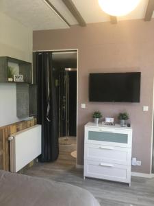 a bedroom with a white dresser with a tv on the wall at Le nid de cigognes in Menchhoffen