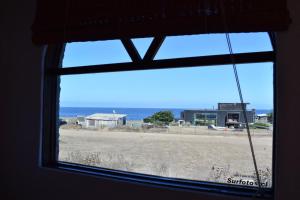 a window with a view of the ocean from a beach at Conviento de Lobos in Pichilemu