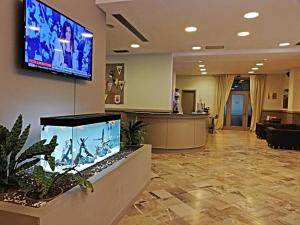 um lobby hospitalar com uma grande tv na parede em Hotel Touring em Falconara Marittima