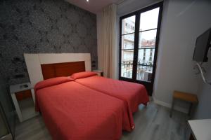 1 dormitorio con cama roja y ventana en Hostal Centro en Soria