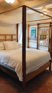 a bedroom with a four poster bed and two windows at Caye Casa in San Pedro