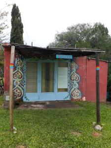 un pequeño edificio con una puerta azul en el césped en Posada Arco Iris en San Marcos Sierras