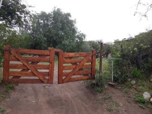 una puerta de madera en un camino de tierra en un campo en Posada Vegetariana Arco Iris en San Marcos Sierras