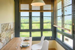 a dining room with a table and chairs and windows at APARTAMENTOS LA LLONGAR in Infiesto