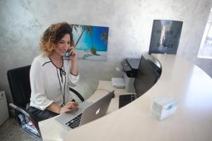 una mujer hablando por un celular en una oficina en Oldwell Hotel, en Tropea