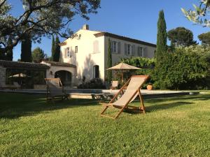two lawn chairs and an umbrella in front of a house at LES BARTAVELLES in Aix-en-Provence