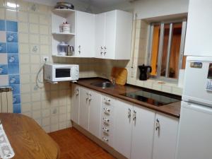 a kitchen with white cabinets and a sink and a microwave at CASA RURAL LA CASILLA DE MILA in Frómista