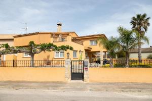 a yellow house with a fence and palm trees at Villa Bo in Deltebre