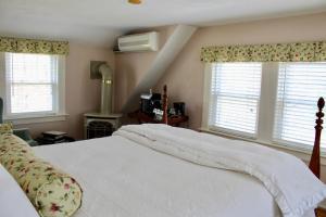 a bedroom with a white bed and two windows at Sugar Hill Inn in Sugar Hill
