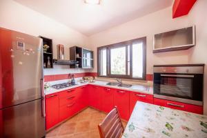 cocina con armarios rojos y nevera de acero inoxidable en Villa Lavanda, en Cefalú