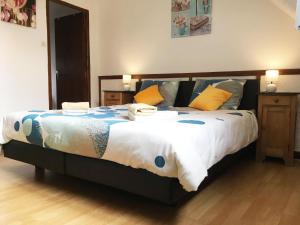 a bedroom with a large bed with yellow and blue pillows at Domaine Les Filloux in Saint-Dizier-Leyrenne