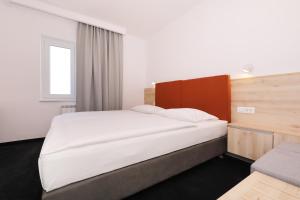 a bedroom with a large white bed and a window at Hotel Mediteran in Zadar