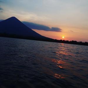 un coucher de soleil sur une étendue d'eau avec une montagne dans l'établissement Hospedaje Bananas, à Altagracia