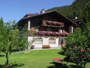 a house with a balcony with flowers on it at Garnì Conturina in Santa Cristina Gherdëina