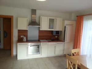 kuchnia z białymi szafkami, kuchenką i lodówką w obiekcie Apparthotel Stoanerhof w mieście Uderns