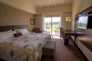 um quarto de hotel com uma cama, uma secretária e uma janela em Melincue Casino & Resort em Melincué