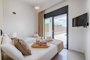 a white room with a bed and a tv and a couch at Prasonisi Villas in Kattavía