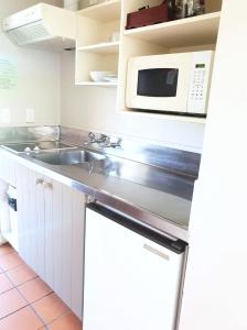 a kitchen with a sink and a microwave at Parklane Motor Lodge in Auckland