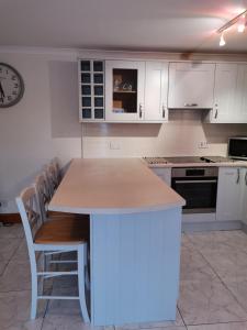 a kitchen with white cabinets and a table with chairs at The Greannan Lower Self catering apartment in Blackwaterfoot