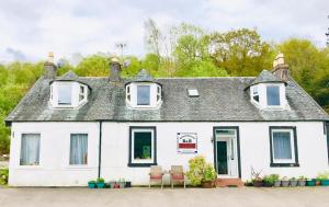 a white house with chairs in front of it at Rowantreebank Bed and Breakfast in Arrochar
