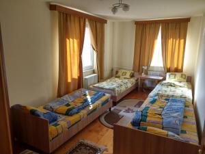 a room with three beds and a table and windows at Lary Hostel in Suceava