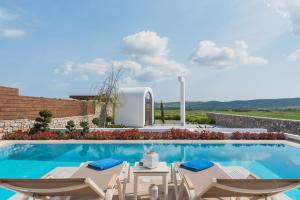 a swimming pool with chairs and a villa at Prasonisi Villas in Kattavía