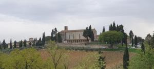 a large building with trees in front of it at Ladybug Apartment in Poggibonsi