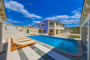 a swimming pool with two lounge chairs next to a house at Villa AnBer in KoruÅ¡ce