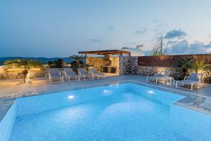 a swimming pool with chairs next to a house at Prasonisi Villas in Kattavía