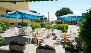 un patio con tavoli, sedie e ombrelloni blu di Villa Verdiana a Nettuno