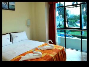 dos toallas de cisne sentadas en una cama con ventana en Alejandra Hotel, en Chiclayo