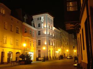 a building with a clock on the side of it at night at Hotel Marmułowski in Wejherowo