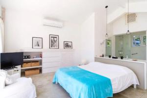 Un dormitorio blanco con una cama y un televisor. en Paraiso Romântico Inesquecível Praia Vermelha do Sul Ubatuba, en Ubatuba