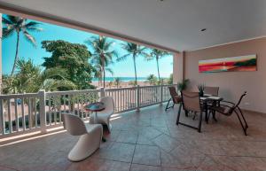 einen Balkon mit Blick auf das Meer und die Palmen in der Unterkunft The Palms Ocean Club Resort in Jacó