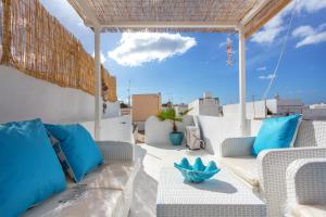 a patio with white chairs and blue pillows at CASA DO PESCADOR by Ammonite&Co in Olhão