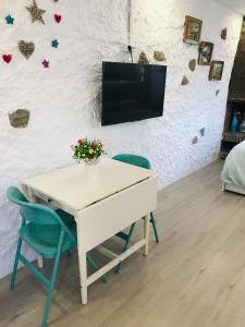 a white table with two chairs and a tv on a wall at Heart of Gracia in Barcelona