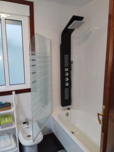a bathroom with a phone on the wall next to a bath tub at apartment garden in Caldas de Reis