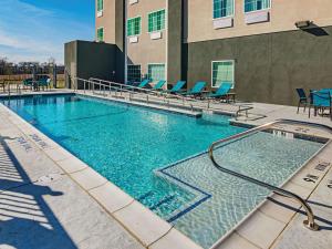una gran piscina con sillas azules y un edificio en La Quinta by Wyndham Dallas - Wylie, en Wylie