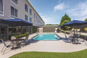a pool with chairs and tables and umbrellas next to a building at La Quinta by Wyndham Columbus North in Columbus