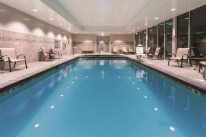 a pool in a hotel with chairs and tables at La Quinta by Wyndham South Jordan in South Jordan