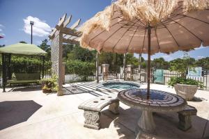 un patio con banco, sombrilla y piscina en La Quinta by Wyndham PCB Coastal Palms, en Panama City Beach