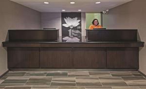 a woman standing at a reception desk in a lobby at La Quinta Inn by Wyndham San Marcos in San Marcos