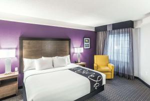 
a hotel room with a bed, chair, and nightstand at La Quinta by Wyndham Flagstaff in Flagstaff
