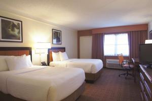 a hotel room with two beds and a flat screen tv at La Quinta by Wyndham Coral Springs University Dr in Coral Springs