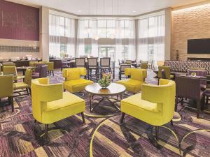 a waiting room with yellow chairs and tables at La Quinta by Wyndham Fort Worth North in Fort Worth